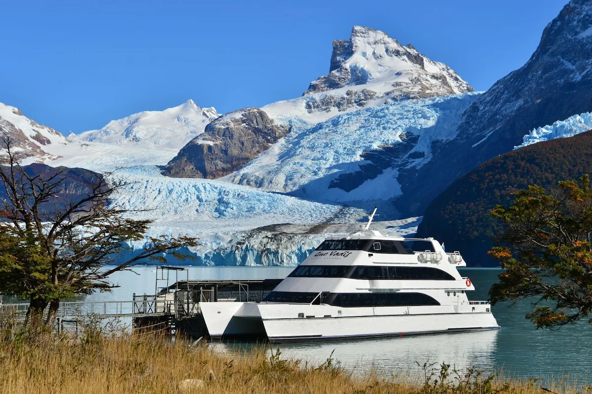 De catamaran ligt bij de aanlegsteiger van Refugio Spegazzini met op de achtergrond de enorme wanden van de Spegazzini gletsjer in het Nationaal Park Los Glaciares.