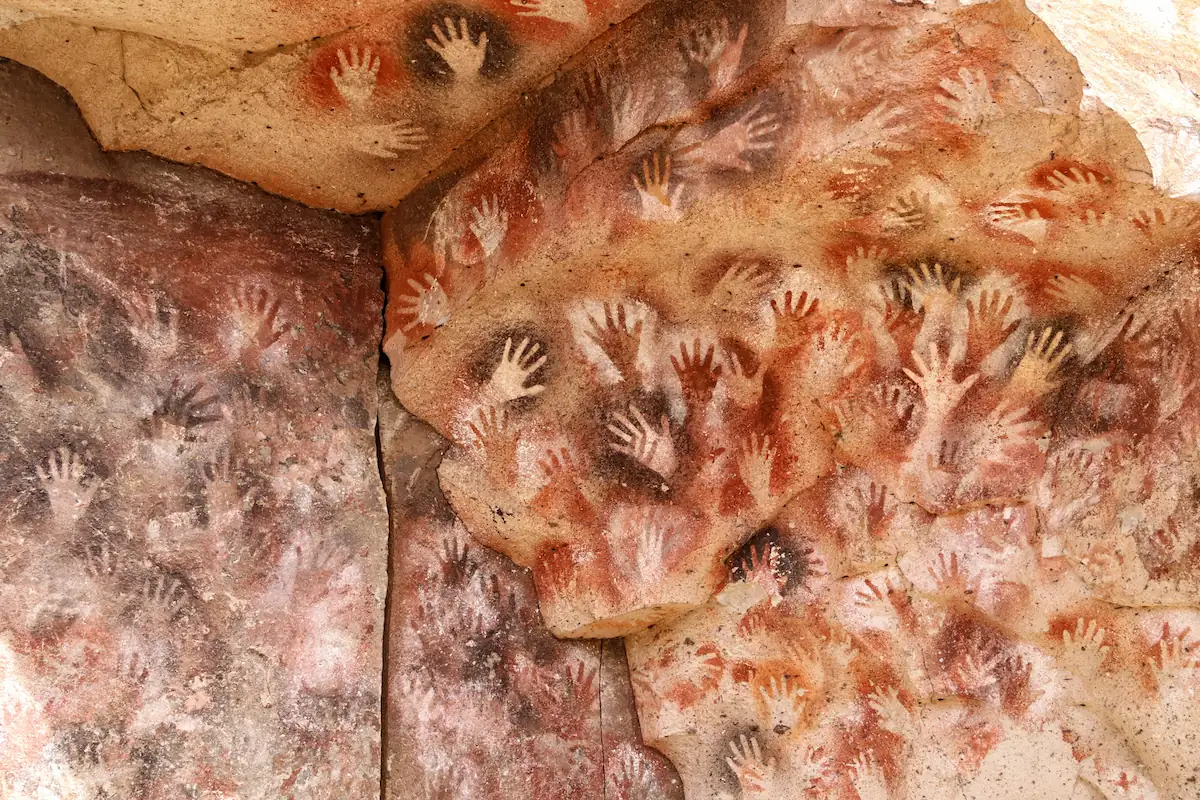 Close-up van de prehistorische handafdrukken in rode en okerkleurige tinten op de rotswanden van de Cueva de las Manos, een UNESCO Werelderfgoedlocatie.