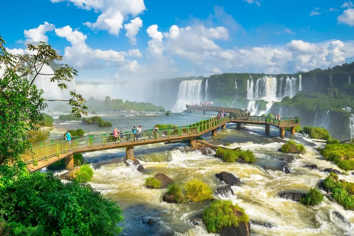 Het indrukwekkende panorama vanaf de Braziliaanse kant Bezoekers wandelen over de beroemde loopbrug aan de Braziliaanse zijde van de Iguazú watervallen met opvliegende nevel en regenbogen.