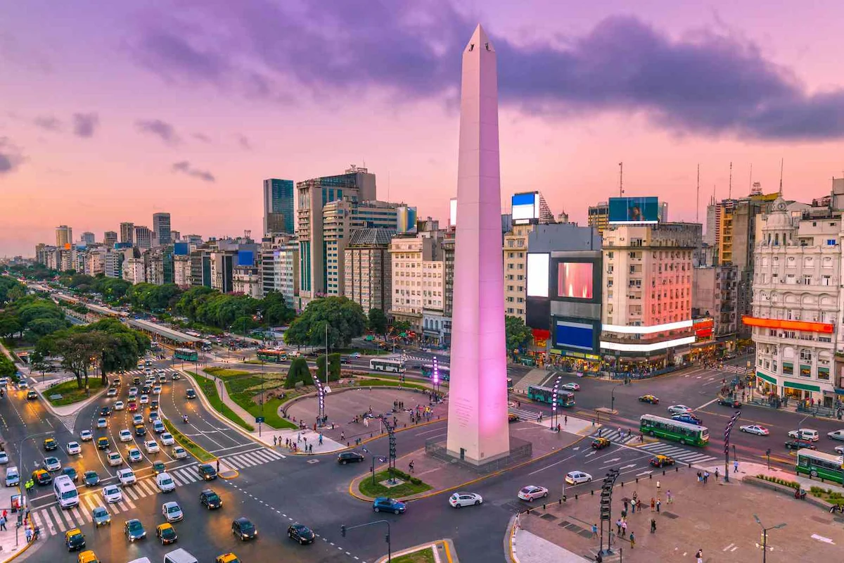 De energie van Buenos Aires bij nacht Een luchtfoto van de verlichte Obelisco en de drukke Avenida 9 de Julio in Buenos Aires tijdens de paars-roze avondschemering.