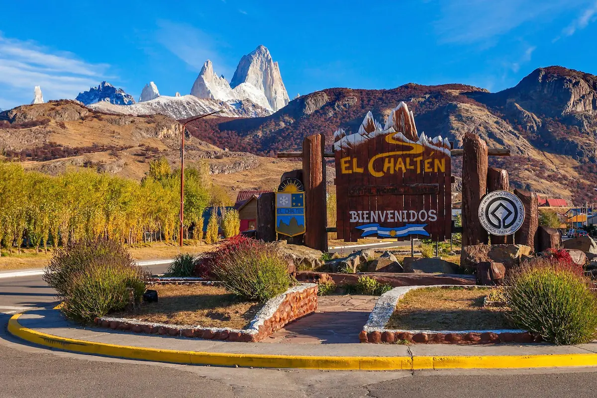 Het iconische houten welkomstbord van El Chaltén, de nationale wandelhoofdstad van Argentinië, met de besneeuwde Fitz Roy-pieken op de achtergrond.