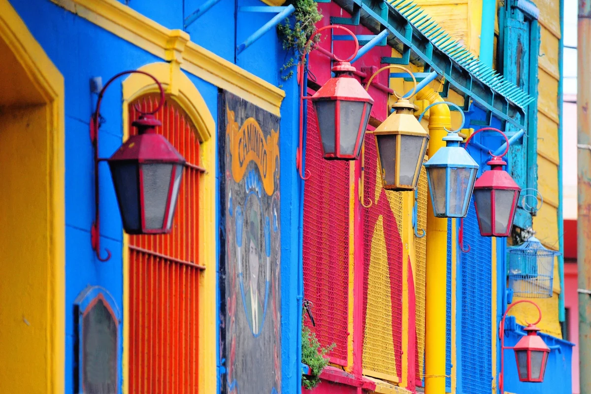 Kleurrijke lantaarns aan de felgeblauw en geel geschilderde muren van de Caminito in de wijk La Boca, Buenos Aires.