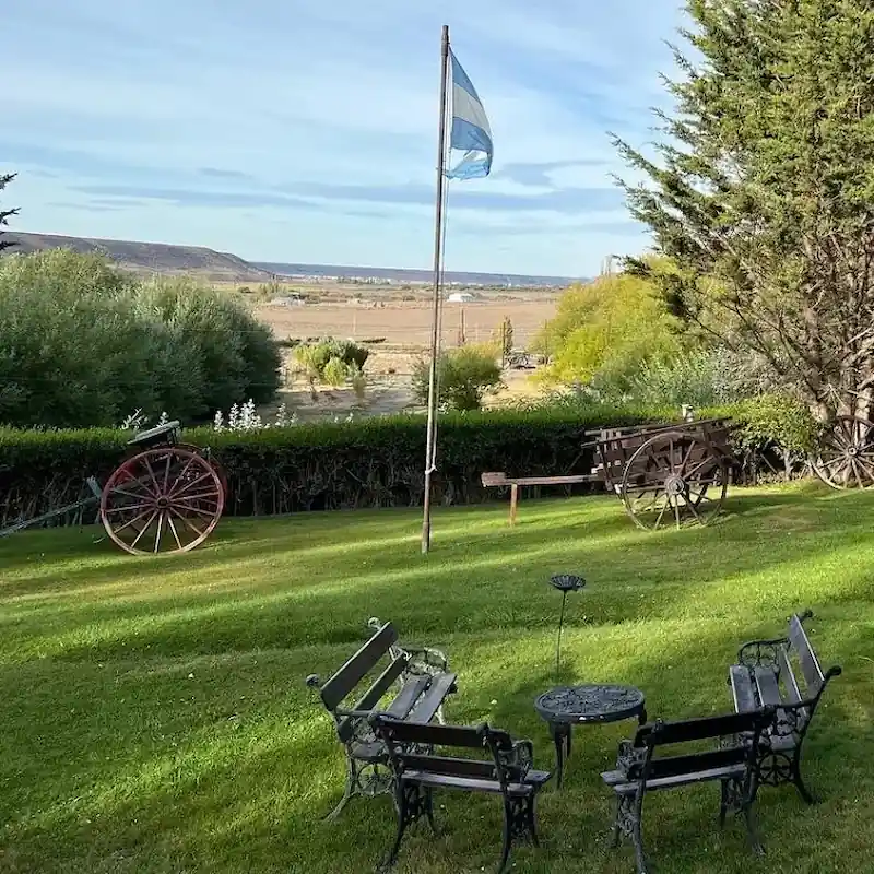 De tuin van Estancia Don José in Río Mayo met antieke karren en uitzicht over de Patagonische steppe.