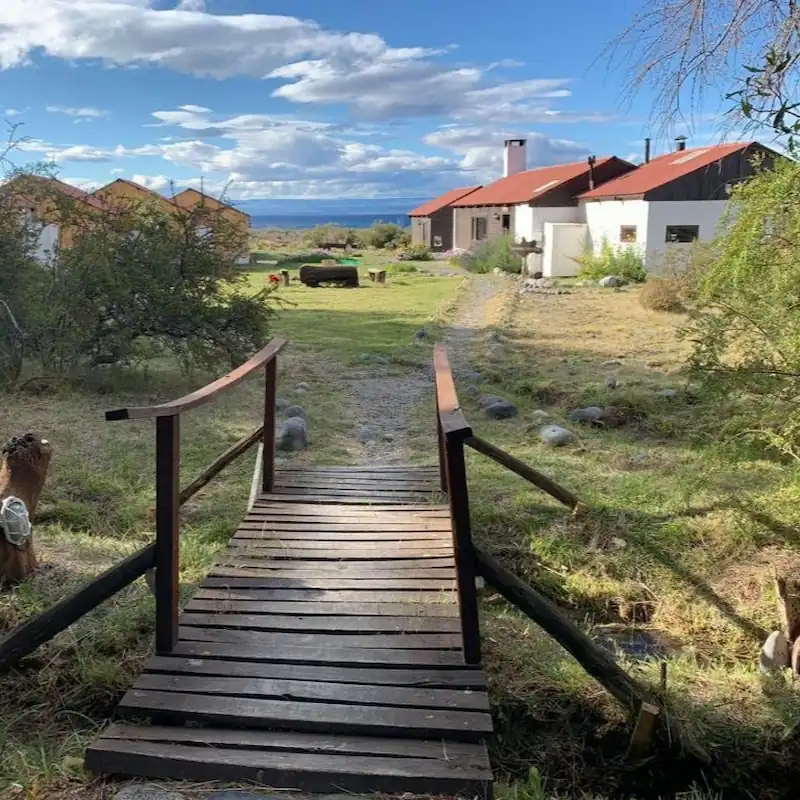 Een houten bruggetje in de tuin van Estancia La Serena met uitzicht op het Lago Buenos Aires in Los Antiguos.