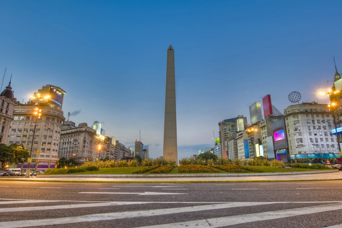 Aankomst in het sfeervolle Buenos Aires De verlichte Obelisk van Buenos Aires op de Avenida 9 de Julio tijdens de avondschemering, met stadslichten en gebouwen.