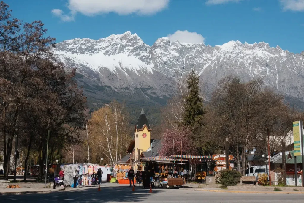 Kleurrijke kraampjes van de Feria Regional op Plaza Pagano in El Bolson met de besneeuwde Cerro Piltriquitron op de achtergrond.